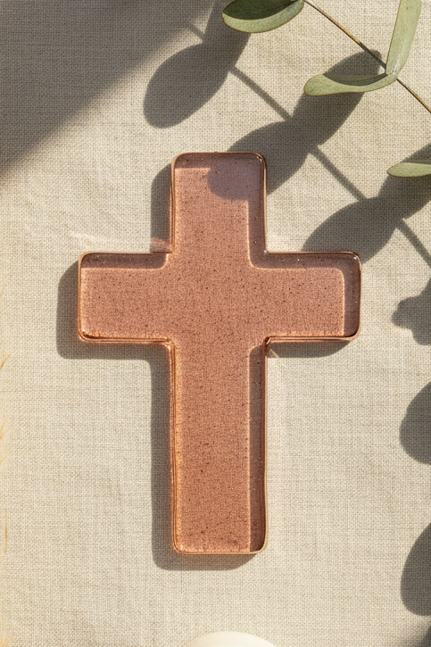 Mauve glass cross on a textured surface with pampas grass and a candle