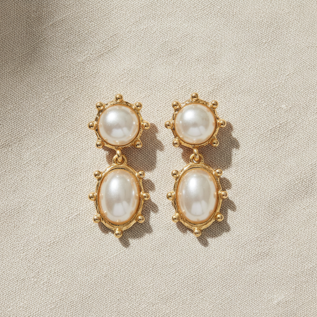 Pair of pearl earrings with gold accents on a beige background by Grace Ann Designs 