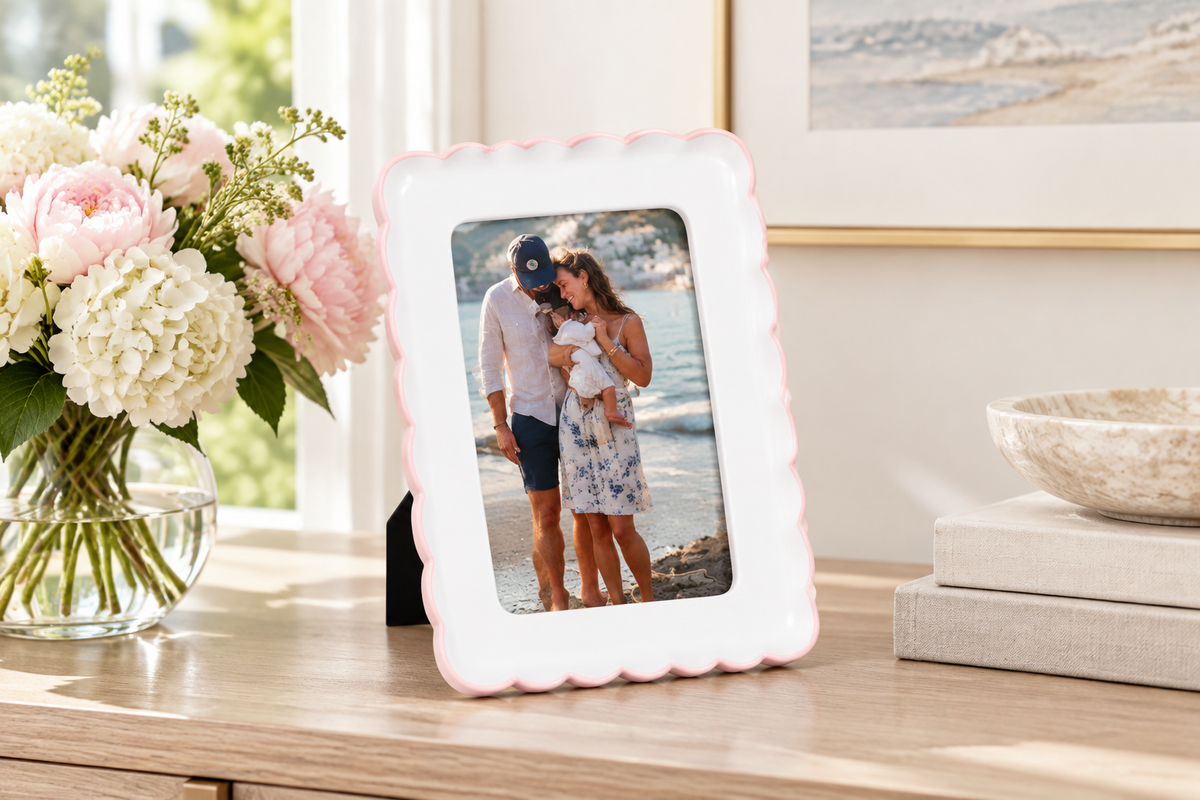 Pink scalloped resin picture frame holding a 4 x 6 vacation photo on an elegant living room console