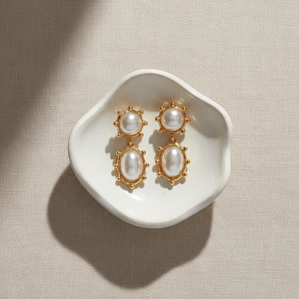 Pair of gold earrings with pearl-like stones on a beige surface by Grace Ann Designs 