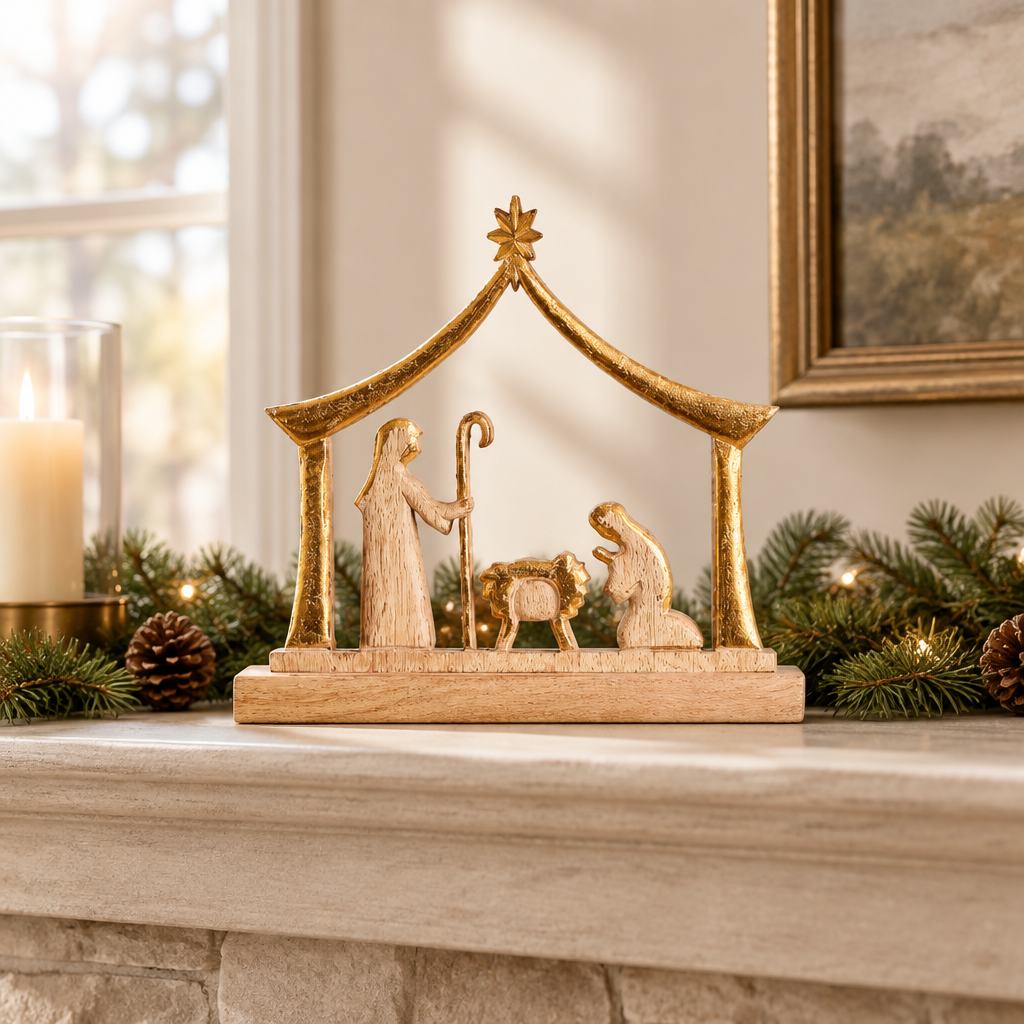 Wood manger nativity with gold-toned star on a mantel with evergreen garland and a candle.