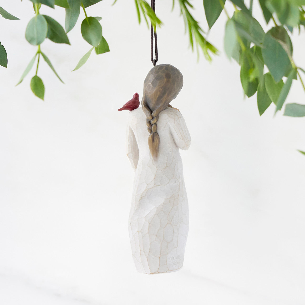 Decorative figurine of a woman with a bird on her shoulder, hanging against a white background.