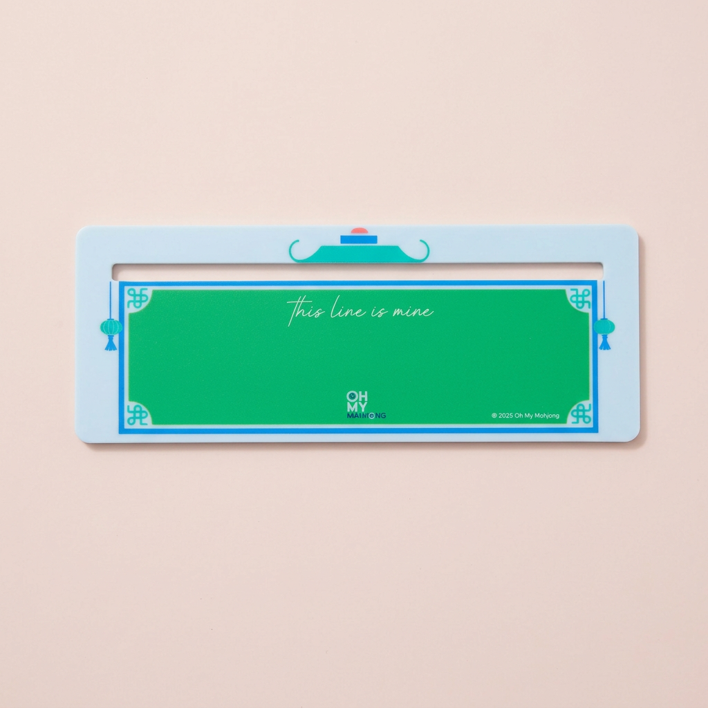 Overhead view of the Oh My Mahjong light blue line finder with a green center and blue borders on a pale blush background.