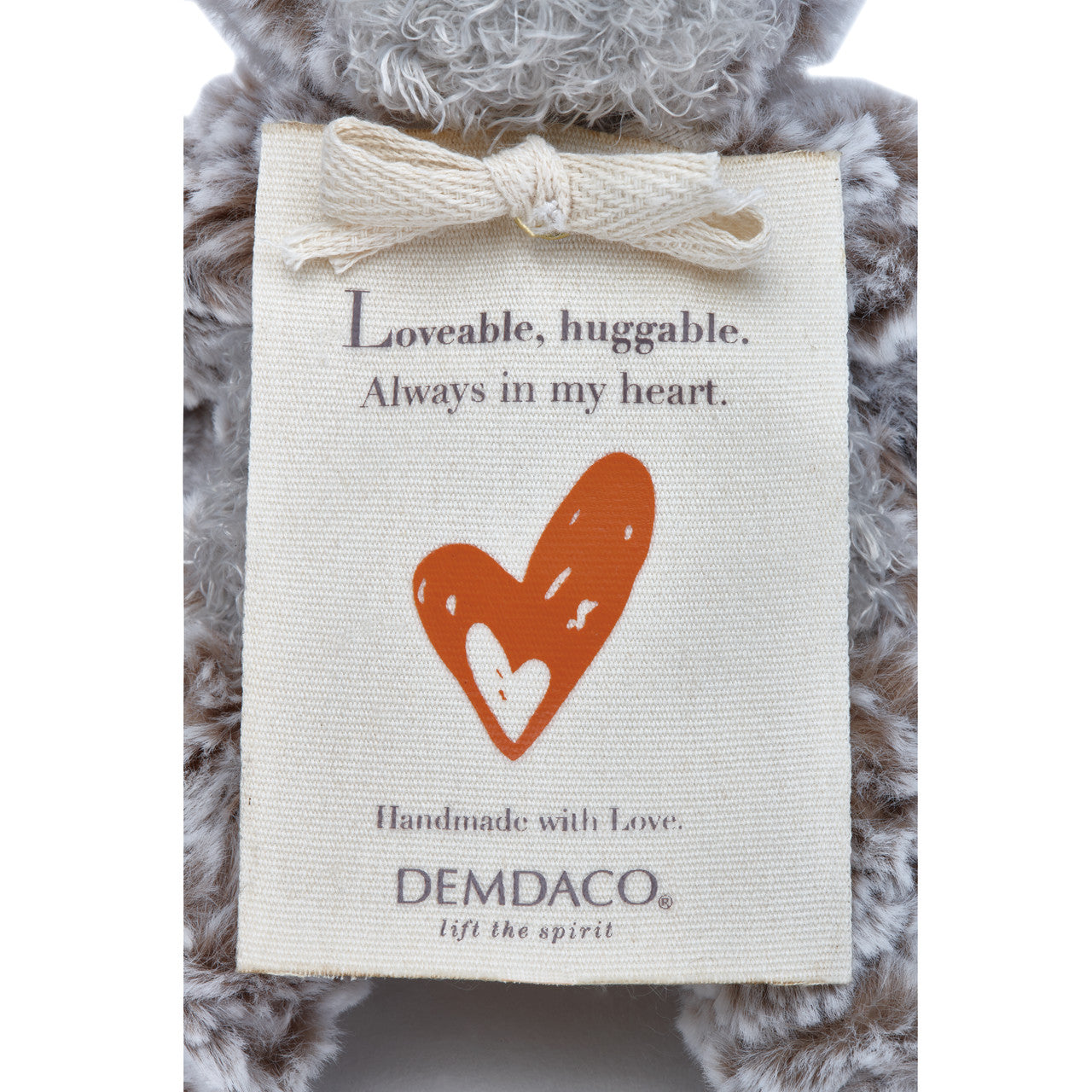 Plush bear with a DEMDACO tag featuring a heart and text.