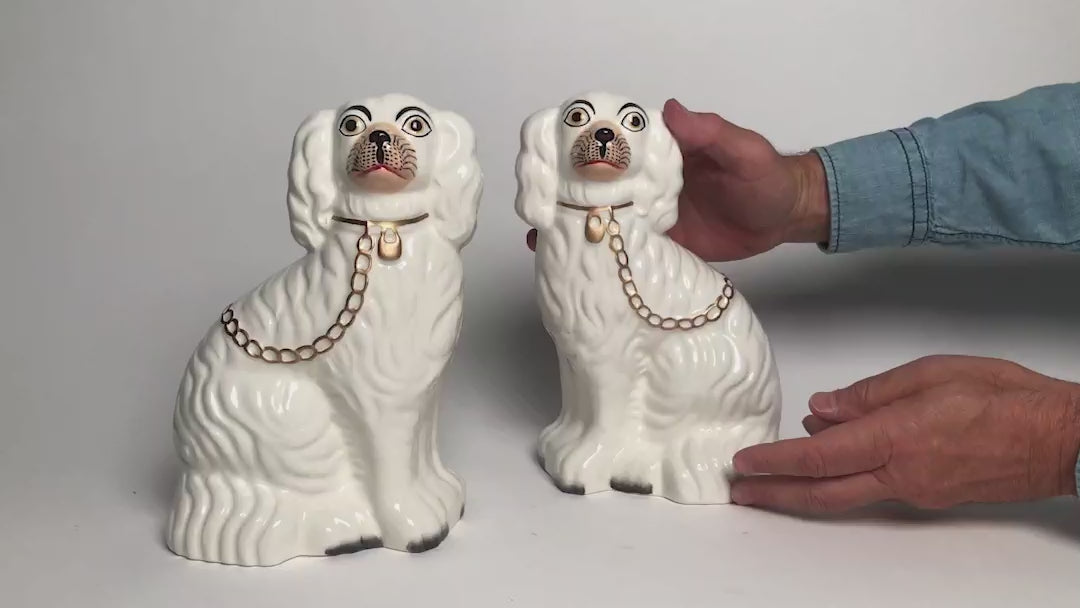 Load video: Video showing two Staffordshire white ceramic dogs facing each other. Demonstrated by a man