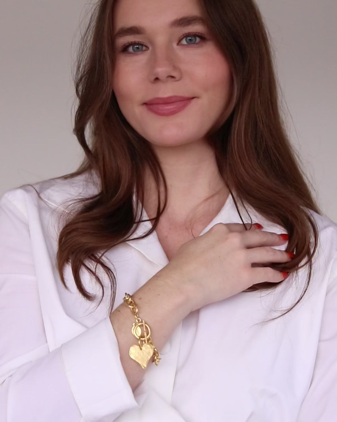 Load video: video of woman in white shirt wearing toggle clasp gold heart bracelet