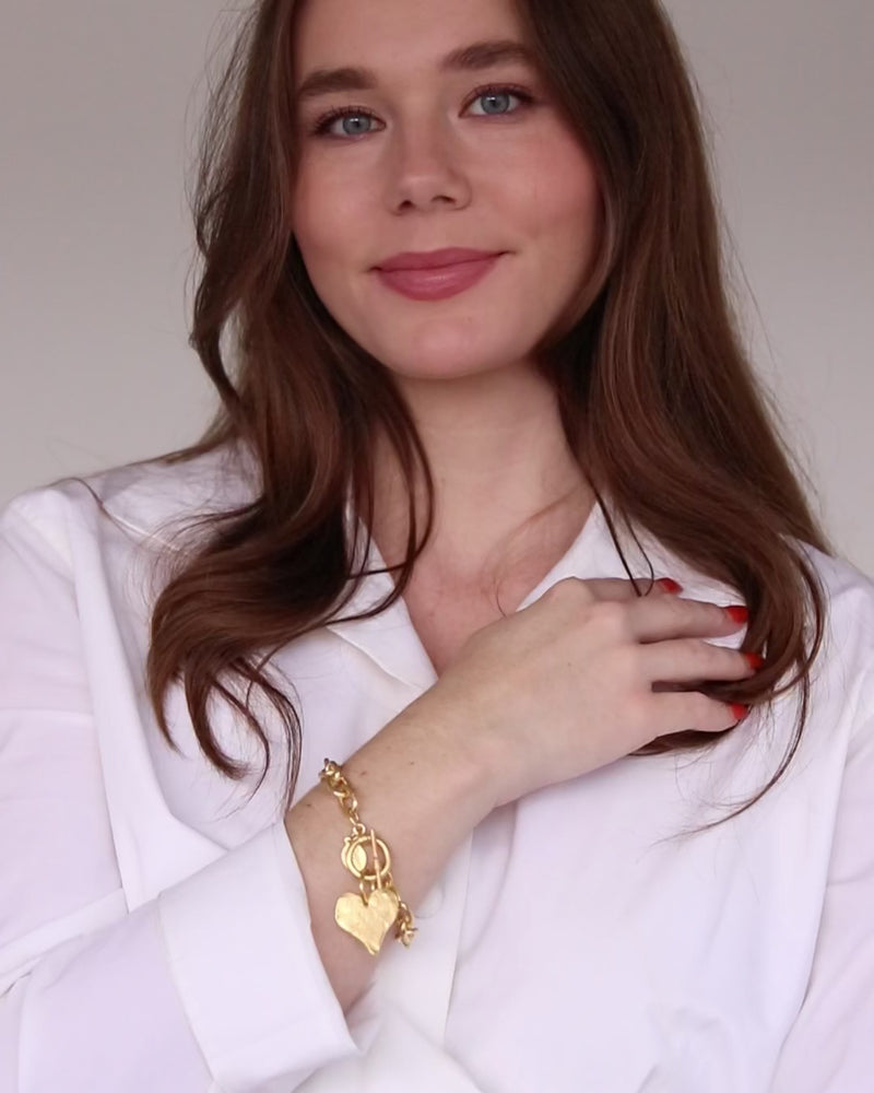 video of woman in white shirt wearing toggle clasp gold heart bracelet