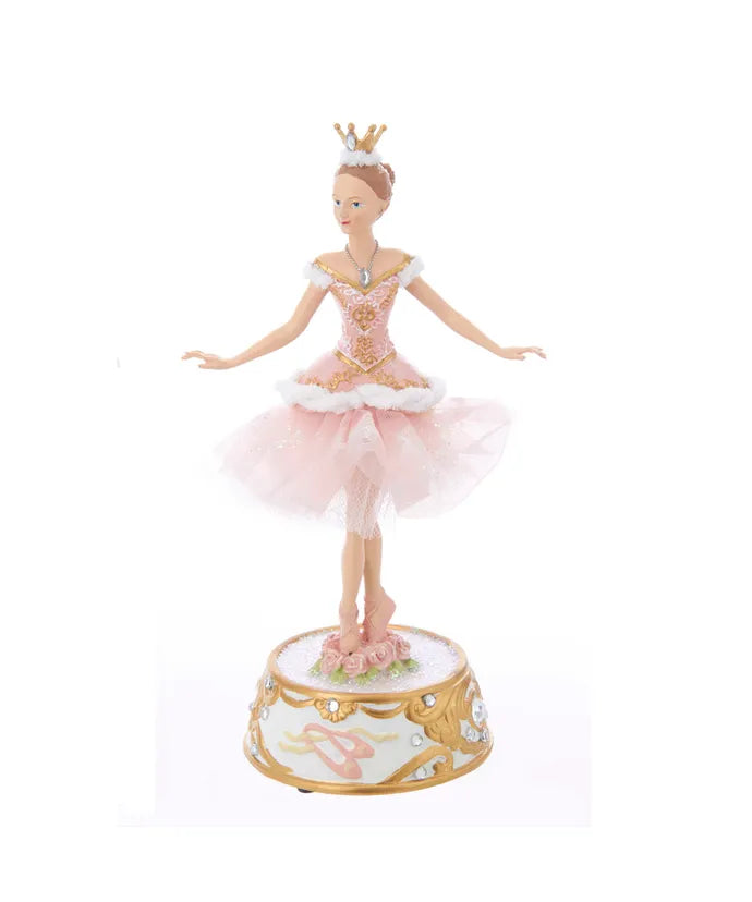Ballerina figurine in a pink dress with a crown on a white background