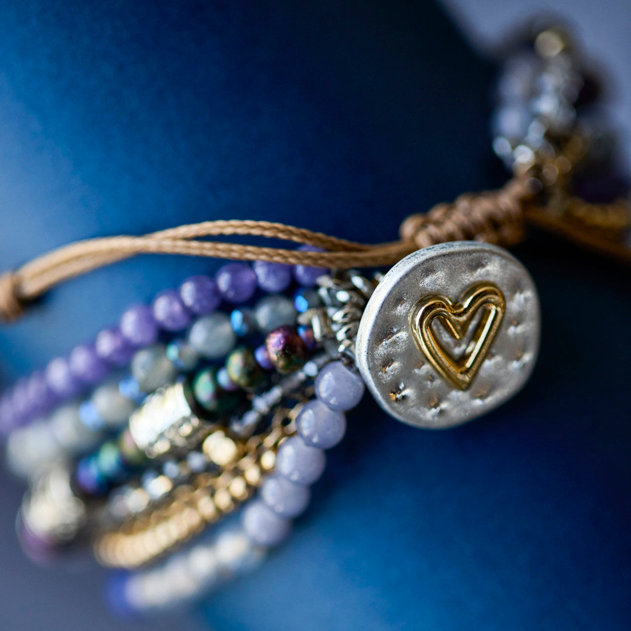 Close-up of a beaded bracelet with a heart-shaped charm on a blue background