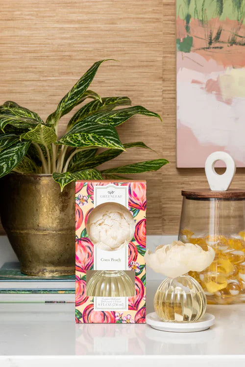 Decorative diffuser with packaging on a surface with a plant and jar in the background