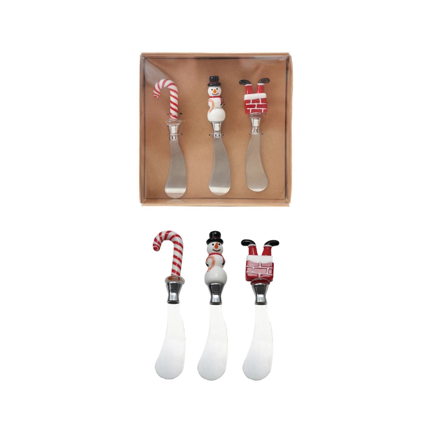 Set of three Christmas-themed butter knives with decorative handles in a box on a white background.